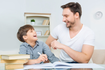 Pleased young father checking homework of son.